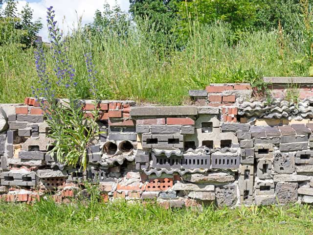 circulair en goed voor insecten: restanten van bouwmaterialen vormen een insectenhotel en tegelijkertijd een speelse afscheiding. 